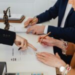Hands signing a divorce decree, with a justice statue nearby, symbolizing legal proceedings.